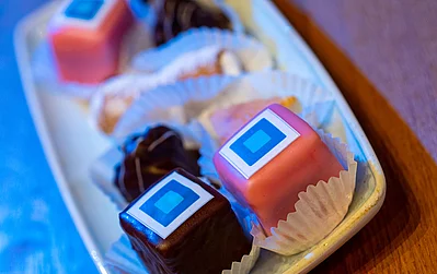 Eine ansprechende Präsentation von kleinen, bunten Desserts auf einem Teller, die in Papierförmchen serviert werden.